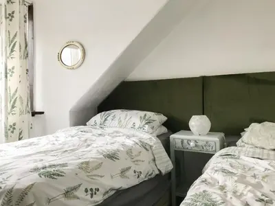 a bedroom with a bed with a green and white comforter at Kitty's Cottage in Girvan