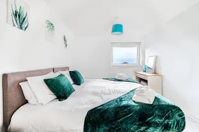 a bedroom with a bed with green pillows and a window at Balloch House -Spacious 3 bed house with on street parking in Kirk of Shotts