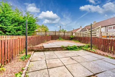 a backyard with a wooden fence and a patio at Scotia House -3 bed house in Larkhall with private driveway in Larkhall