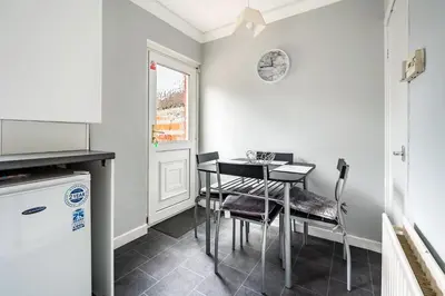 a kitchen with a table and chairs and a refrigerator at Scotia House -3 bed house in Larkhall with private driveway in Larkhall