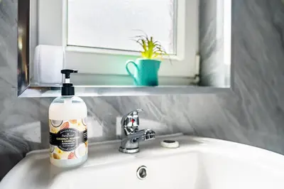a bottle of soap sitting on a bathroom sink at Scotia House -3 bed house in Larkhall with private driveway in Larkhall