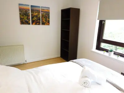 a bedroom with a white bed and a window at Charming 2 bed apt close to City and SEC Hydro in Glasgow