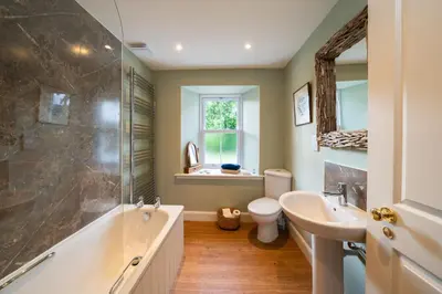 a bathroom with a tub and a toilet and a sink at Riverside Cottage, Bridge of Balgie, Glenlyon, Perthshire in Bridge of Balgie