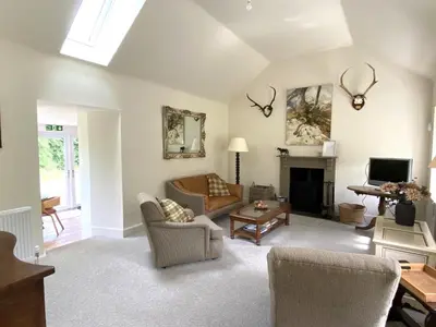 a living room with a couch and a tv at Riverside Cottage, Bridge of Balgie, Glenlyon, Perthshire in Bridge of Balgie