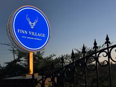 a sign for a firm village next to a fence at FINN VILLAGE 
