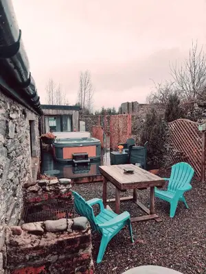 a patio with a table and chairs and a grill at Fyne Byre Cottage - Barn Conversion with Hot Tub in Cairndow