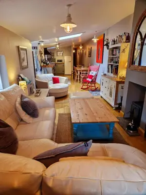 a living room with two couches and a table at Fyne Byre Cottage - Barn Conversion with Hot Tub in Cairndow