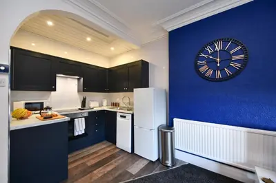 a kitchen with a large clock on a blue wall at The Wee Lion in Troon