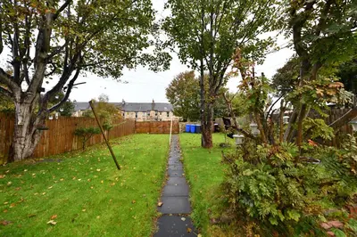a path in a yard with trees and a fence at The Wee Lion in Troon