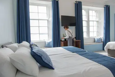 a woman standing in a bedroom with a large bed at Coorie in Dunfermline