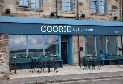 a cafe with tables and chairs in front of a store at Coorie in Dunfermline