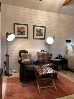 a living room with a chair and a bed at Charming stone Bothy at Loch Lomond in Luss