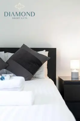 a bed with a black and white pillow and a nightstand at Cosy 2 Bed Apt West End Edinburgh FREE PARKING in Edinburgh