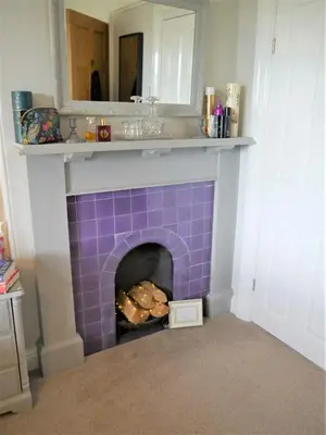 a living room with a purple tile fireplace at Glaisters Farmhouse in Castle Douglas