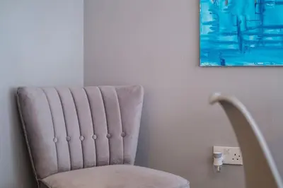 a chair in a room with a painting on the wall at Monicas Apartment Lovely ground floor 2 bedroom serviced apartment in Coatbridge