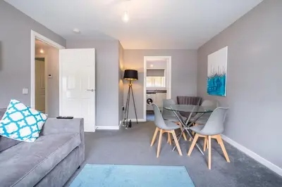 a living room with a couch and a table and chairs at Monicas Apartment Lovely ground floor 2 bedroom serviced apartment in Coatbridge