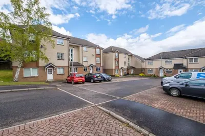 a parking lot with cars parked in front of buildings at Monicas Apartment Lovely ground floor 2 bedroom serviced apartment in Coatbridge