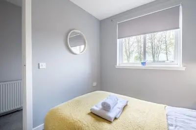 a white bedroom with a bed and a window at Monicas Apartment Lovely ground floor 2 bedroom serviced apartment in Coatbridge