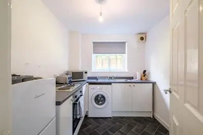 a white kitchen with a washer and dryer in it at Monicas Apartment Lovely ground floor 2 bedroom serviced apartment in Coatbridge