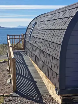 a building with a wooden walkway next to the ocean at Dalrigh Pod in Onich