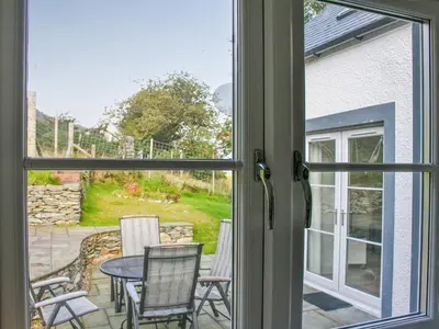 a window view of a patio with a table and chairs at Sqlarran Cottage in Lochranza