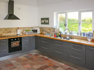 a kitchen with gray cabinets and a sink at Sqlarran Cottage in Lochranza