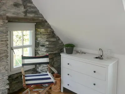 a room with a dresser and a chair next to a window at Sqlarran Cottage in Lochranza