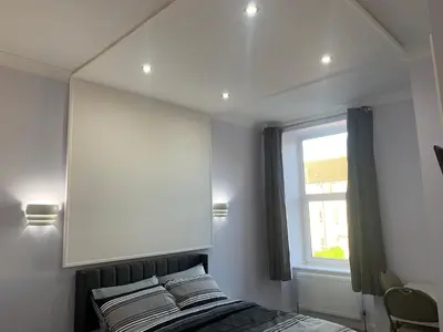 a bedroom with a bed with a mirror and a window at Ibrox Argyll Inn in Glasgow