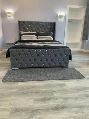 a bedroom with a black bed and a wooden floor at Ibrox Argyll Inn in Glasgow