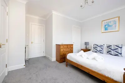 a white bedroom with a bed and a dresser at JOIVY Modern Flat with Free Parking in Edinburgh