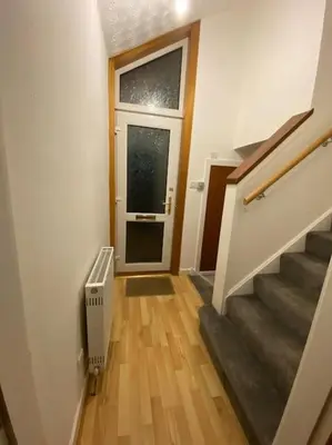 a hallway with stairs and a door with a window at 3 bedroom home-inverkeithing in Fife