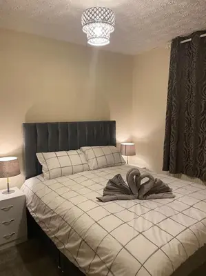 a bedroom with a large bed with a black headboard at 3 bedroom home-inverkeithing in Fife