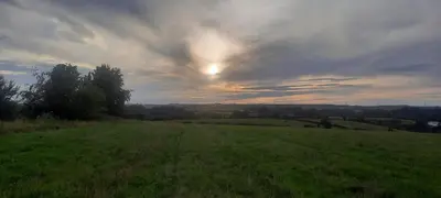 a green field with the sunset in the sky at Lanarkshire Apartment- Views- Sleeps 4- Balcony in Larkhall
