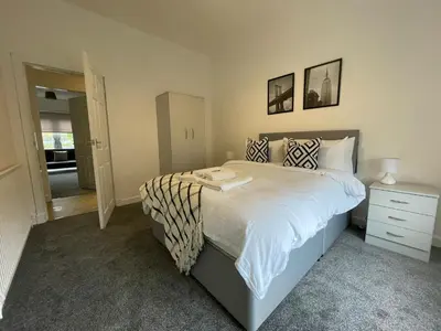 a bedroom with a king sized bed with a night stand at Cardonald House in Glasgow