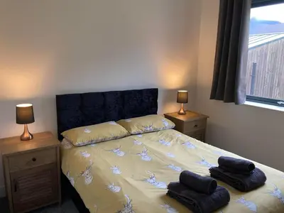 a bedroom with a bed with two night stands and two lamps at Svarga Mountain View in Kinlochleven