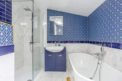 a blue tiled bathroom with a tub and a sink at Svarga Mountain View in Kinlochleven