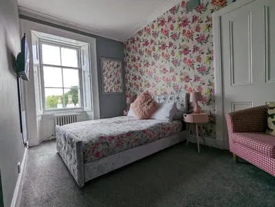 a bedroom with a bed with floral wallpaper and a window at Bonnyside House in Bonnybridge