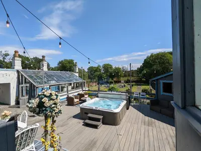 a patio with a hot tub on a deck at Bonnyside House in Bonnybridge