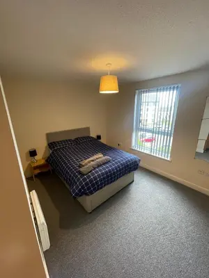 a bedroom with a bed and a large window at Ferry Gait Apartments in Edinburgh