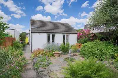 a small white house in the middle of a garden at Silver Lodge in Creetown