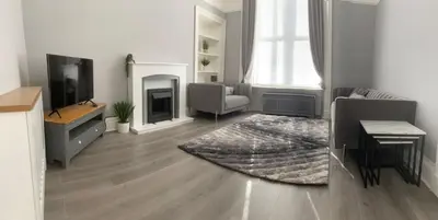 a living room with a television and a couch and a rug at The Princess Flat, Helensburgh. in Helensburgh
