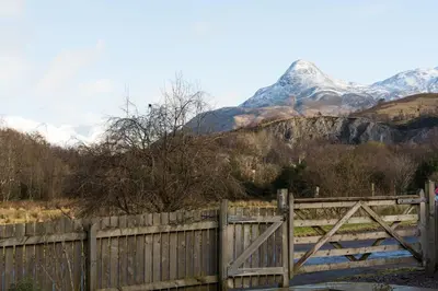 a wooden fence with a mountain in the background at The Nest - small double room nr Glencoe in Ballachulish