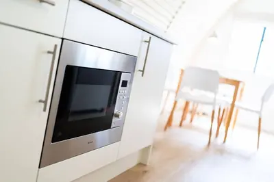 a microwave oven in a white cabinet in a room at Cultybraggan Hut 37 in Comrie