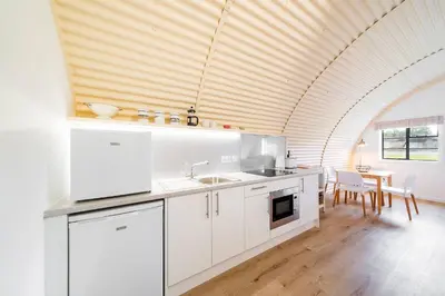 a kitchen with white cabinets and a wooden ceiling at Cultybraggan Hut 37 in Comrie
