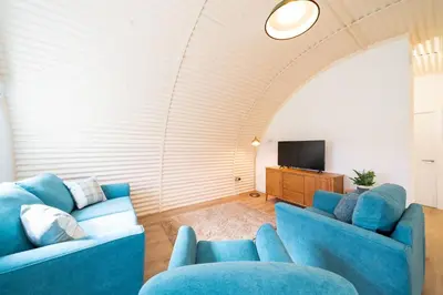 a living room with two blue couches and a television at Cultybraggan Hut 37 in Comrie