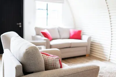 a living room with two white couches and pink pillows at Cultybraggan Hut 36 in Mill of Fortune