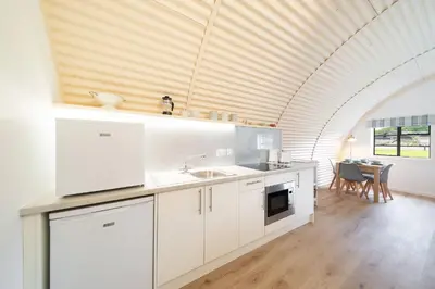 a kitchen with white cabinets and an arched ceiling at Cultybraggan Hut 36 in Mill of Fortune