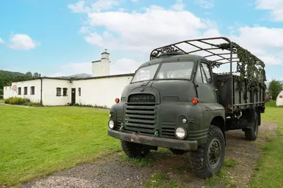 a green truck parked in front of a building at Cultybraggan Hut 36 in Mill of Fortune