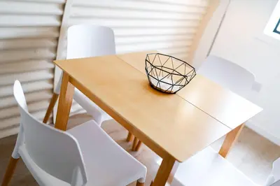 a wooden table with white chairs in a room at Cultybraggan Hut 35 in Comrie