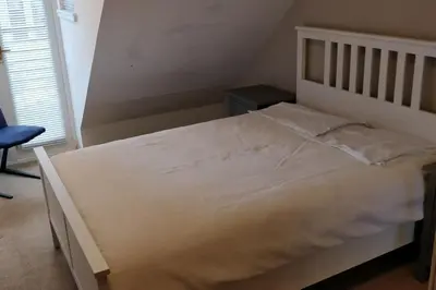 a bedroom with a white bed with a chair and a window at West End & EICC with Parking in Edinburgh